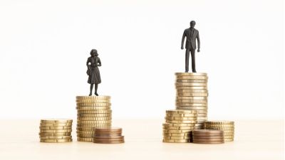 Gender Wage gap concept Man and woman figurines standing on top of the pile of coins